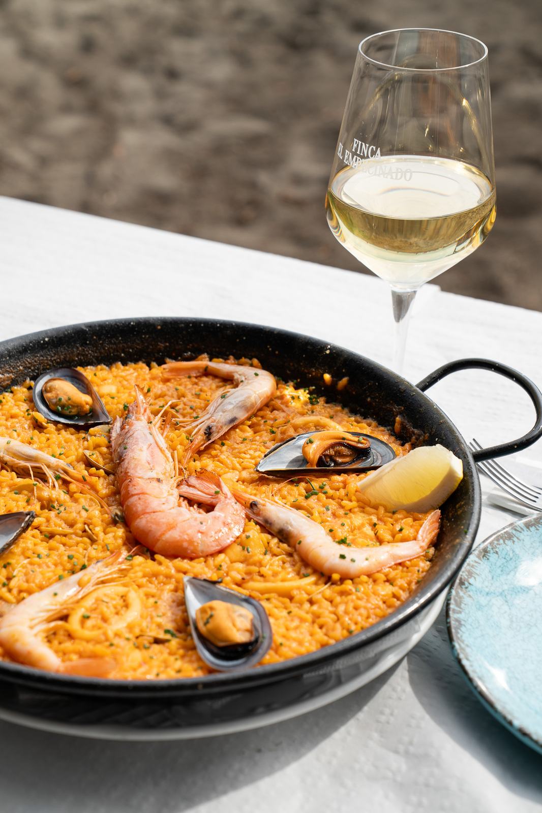 Paella de marisco en la mesa con vino blanco